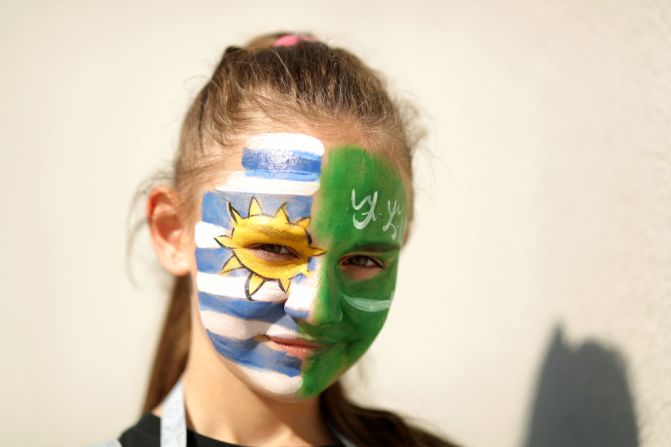 Un chica con el rostro pintado con las banderas de Arabia Saudita y Uruguay posa para una foto.