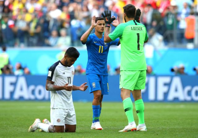 Johan Venegas de Costa Rica se arrodilla en la cancha al final del encuentro con Brasil, mientras Philippe Coutinho y Alisson celebran la victoria en el encuentro.