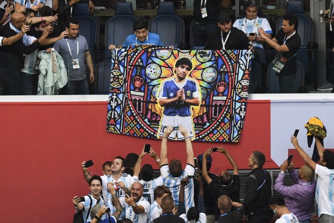 Diego Maradona asiste al encuentro entre Argentina y Nigeria con un póster de sí mismo dibujado como un santo.