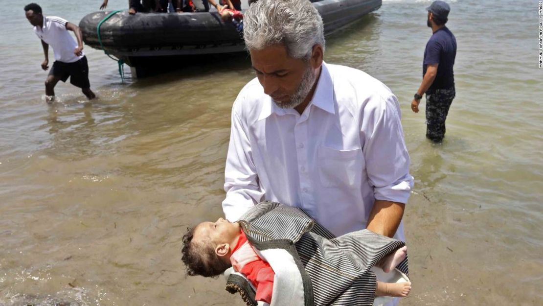 Un hombre lleva el cuerpo de uno de los tres bebés muertos en el Mediterráneo.