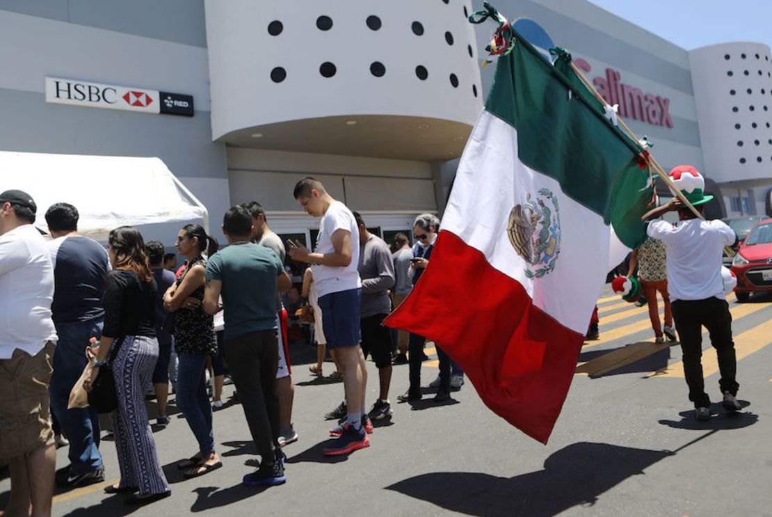 Un vendedor ofrece banderas de México a las personas formadas para votar en Tijuana.