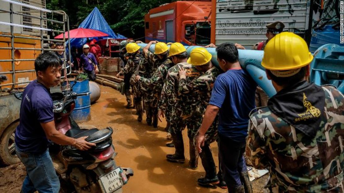 Algunos rescatistas cargan el equipo pesado de bombeo de agua a la cueva Tham Luang Nang Non.