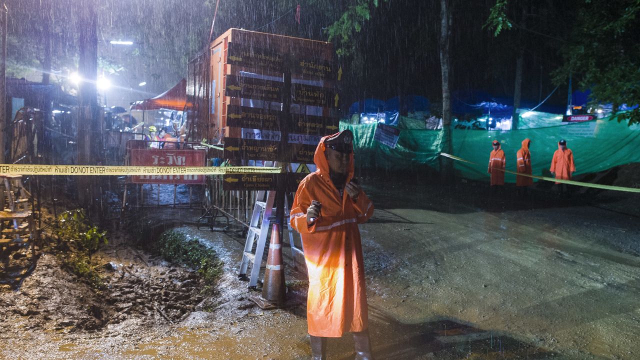 A Thai policeman guards an area under rainfall near the Tham Luang cave at the Khun Nam Nang Non Forest Park in Mae Sai district of Chiang Rai province on July 7, 2018, as rescue operation continues for the 12 boys and their football team coach. - Scrawled deep inside a mountain in northern Thailand, heartwarming fragments of communication from trapped youngsters have reached families keeping vigil for two excruciating weeks at the entrance to the cave complex. (Photo by Ye Aung THU / AFP)