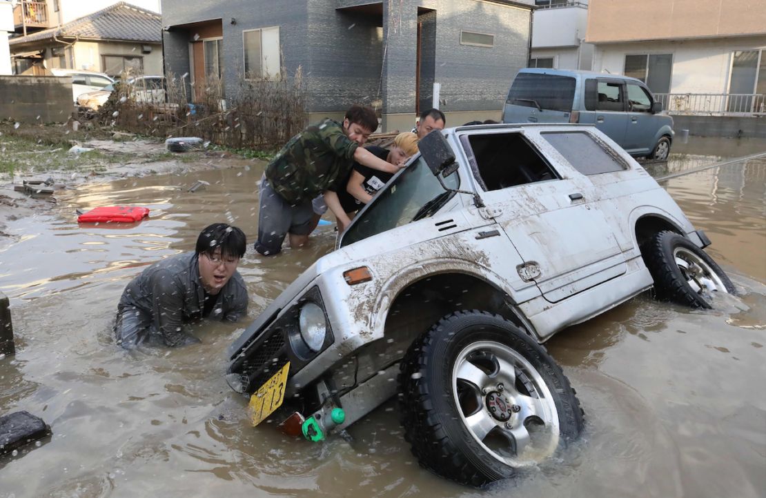 Residentes tratan de levantar un vehículo atrapado por una inundación en Kurashik, en la prefectura de Okayama el 9 de julio de 2018.