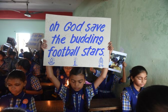 En la India niños de colegio sostienen pancartas y fotos durante un evento de oración por la seguridad de los niños que hasta el domingo 9 de julio no habían sido rescatados.