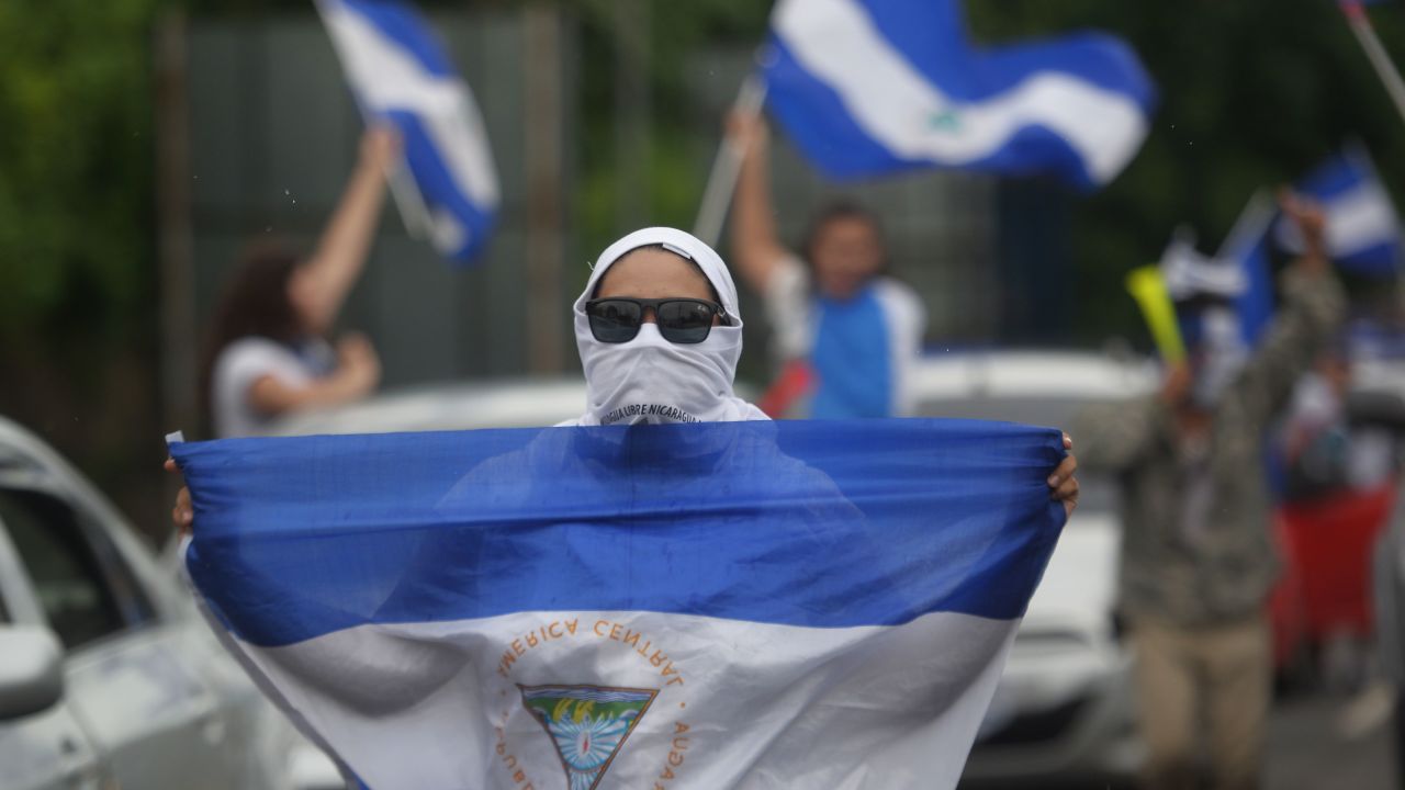 A demonstrator holds a Nicaraguan flag during the march in cars and motorcycles from Managua to Ticuantepe, 15km south of Managua, demanding the resignation of President Daniel Ortega and the end of the state repression, on July 15, 2018. - More than 280 people have been killed since the start of a popular uprising against Nicaraguan President Daniel Ortega in April 18. (Photo by MARVIN RECINOS / AFP)
