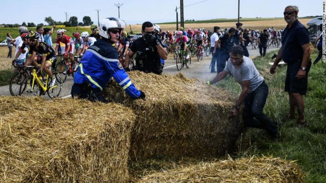 Los gendarmes retiran las rumas de heno colocados colocaron en la ruta del Tour de Francia.