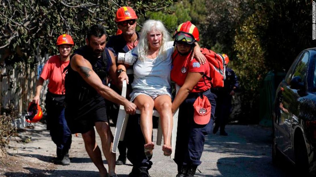 Miembros de los equipos de rescate llevan a una mujer herida en los incendios de Mati, en Grecia.