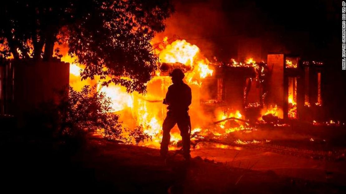 Un bombero lucha contra el fuego frente a una una casa en Redding, California.