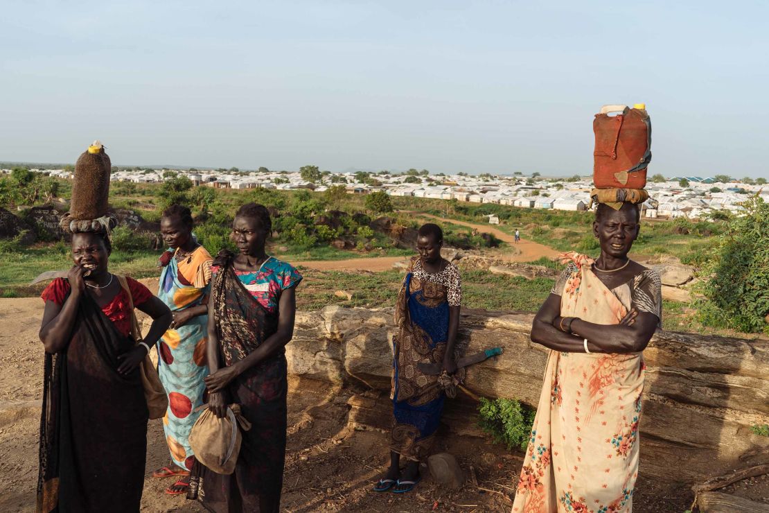 Las mujeres de Sudán del Sur esperan que otras se unan en el camino hacia el bosque para obtener leña.