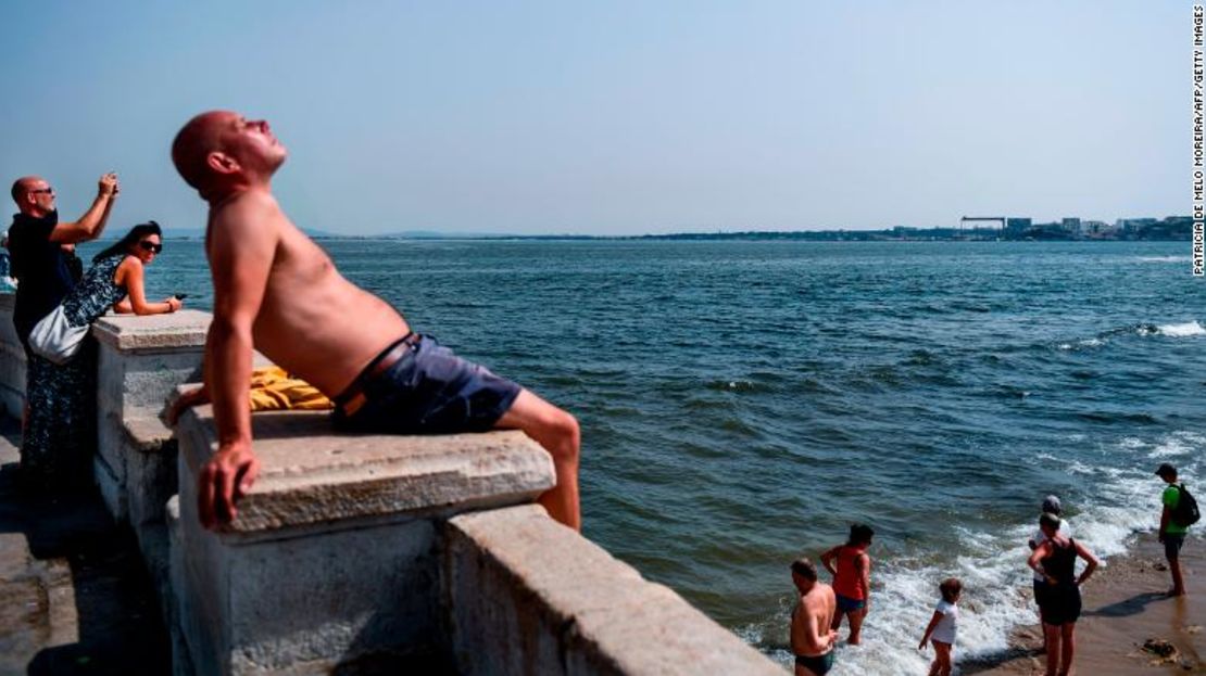 Un hombre toma el sol el viernes mientras otros se refrescan en el río Tajo, en Lisboa, Portugal.