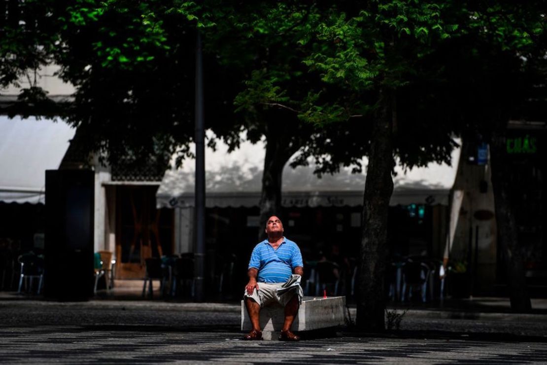 Un hombre se sienta al sol en una plaza de Lisboa, Portugal. (Photo by PATRICIA DE MELO MOREIRA / AFP)