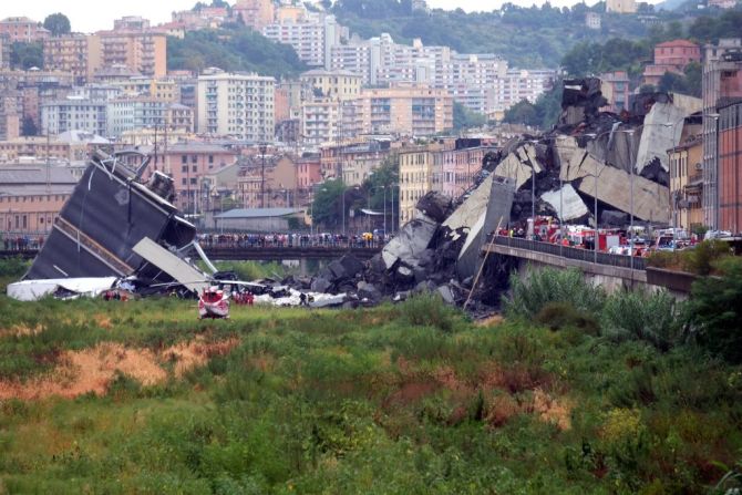 Vista general del colapso del puente. Varios rescatistas avanzan entre los escombros del viaducto que ya deja decenas de víctimas mortales y varios heridos.