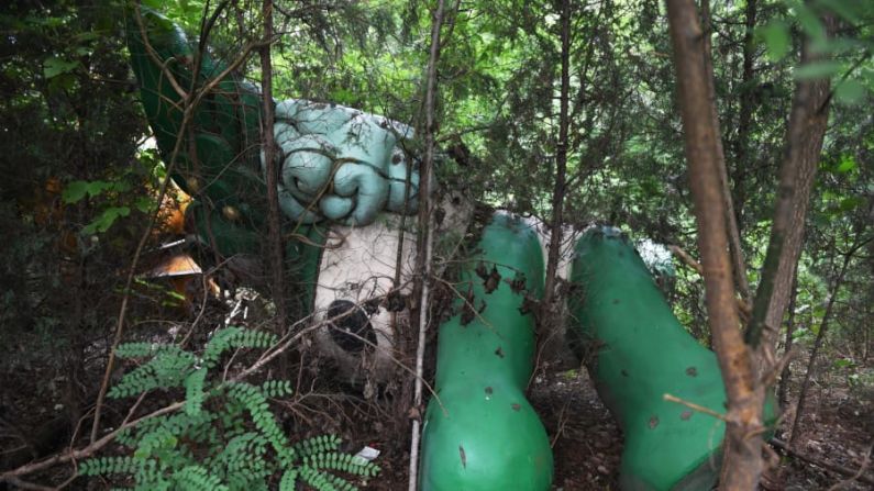 Reclamado por naturaleza: Nini, otra de las mascotas de los Juegos, se ve entre árboles detrás del centro comercial abandonado y nunca terminado en Beijing.