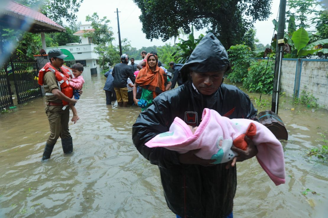 Bomberos y rescatistas evacuan a vecinos en un bote inflable de una zona inundada del distrito Ernakulam, en el estado indio de Kerala.