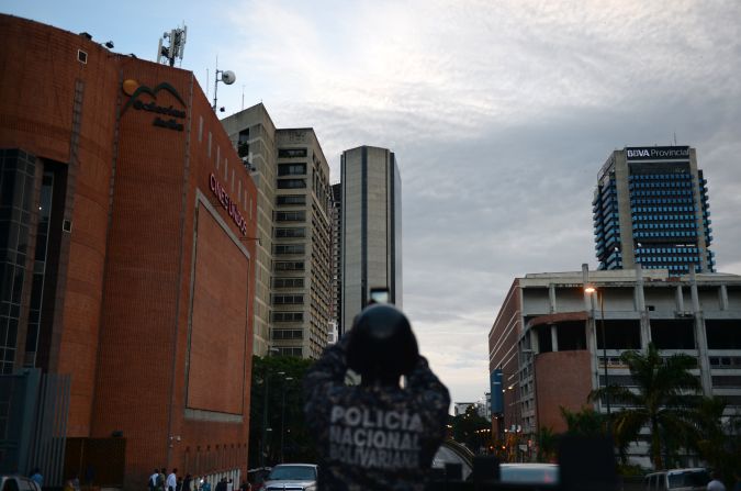 Un policía toma una foto de la Torre de David. Inicialmente era la torre de oficinas Confinanzas e incluso tenía helipuerto. Su construcción se paralizó a mediados de los años 90 cuando el banco que la realizaba quebró.