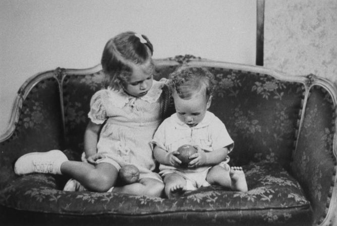 John McCain se sienta en un sofá con su hermana, Sandy, en una reproducción de una foto de familia tomada alrededor de 1938. McCain nació en 1936 de Roberta McCain y John McCain Jr., un almirante de la Armada.