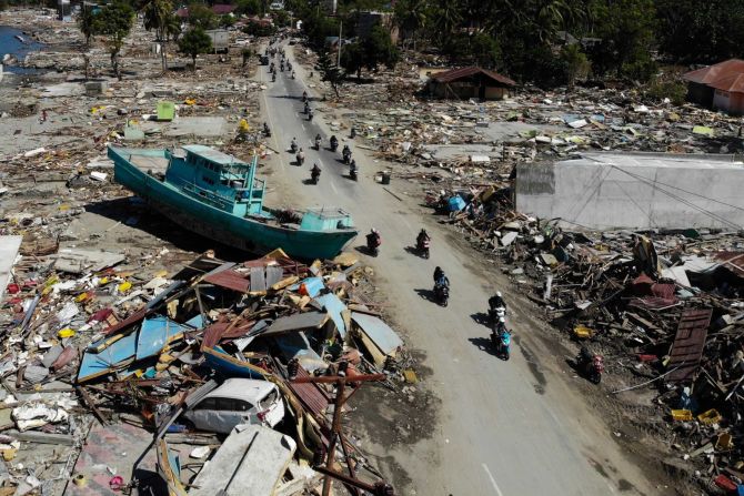 Personas pasan al lado de un barco y otros escombros en Palu, el 1 de octubre.