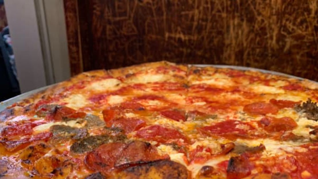 Una pizza de salchicha y pepperoni de John's of Bleecker Street se conserva crujiente pese a la pesada porción de carne.