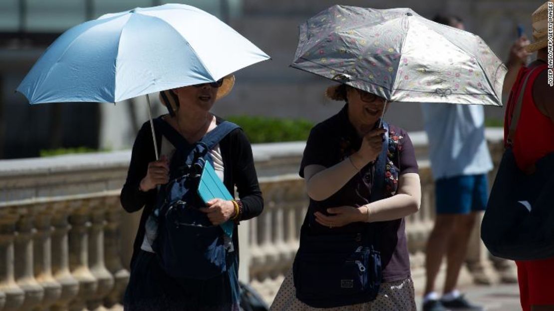 Turistas se protegen con sombrillas del sol y el calor en Barcelona el 28 de junio.