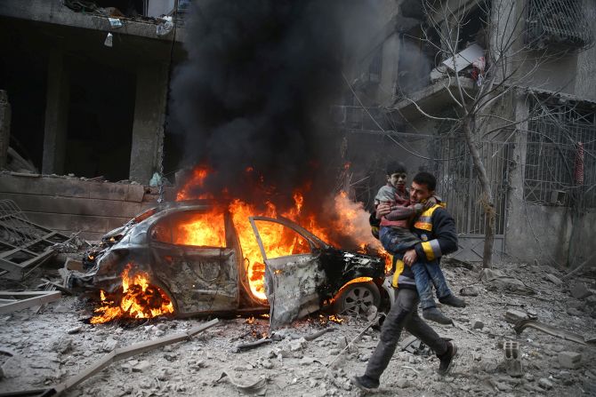 6 de enero - Un miembro de los Cascos Blancos, el grupo de rescate voluntario también conocido como Defensa Civil Siria, lleva a un niño herido después de un ataque aéreo en el enclave sirio de Guta Oriental. Los Cascos Blancos reportaron docenas de ataques aéreos en el área ese día.