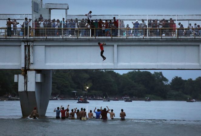 20 de octubre - un migrante salta de un puente para ingresar a México desde Guatemala. Grupos de migrantes centroamericanos han estado viajando a través de México en su búsqueda para ingresar a Estados Unidos. John Moore / Getty Images