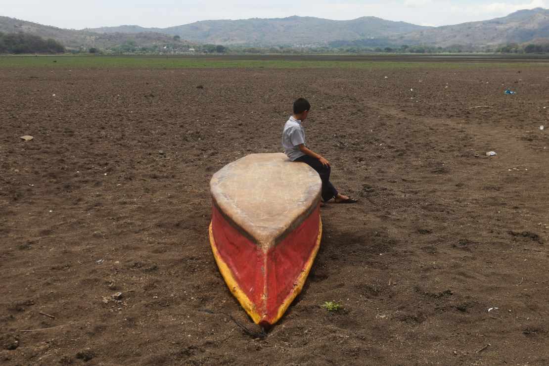 Un niño se sienta en un bote abandonado en lo que queda del lago Atescatempa, que desapaeció debido a la sequía y las altas temperaturas, en Atescatempa, a 174 kilómetros al sureste de la ciudad de Guatemala.