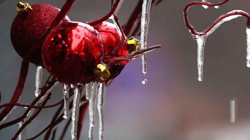 Rusia — Adornos navideños cubiertos de hielo colgados de un árbol en la Plaza Manezhnaya de Moscú. La Iglesia Ortodoxa Rusa aún utiliza el antiguo Calendario Juliano, por lo que el 7 de enero es Navidad para la mayoría de los cristianos en Rusia. Las muñecas anidadas con motivos navideños son una decoración popular.