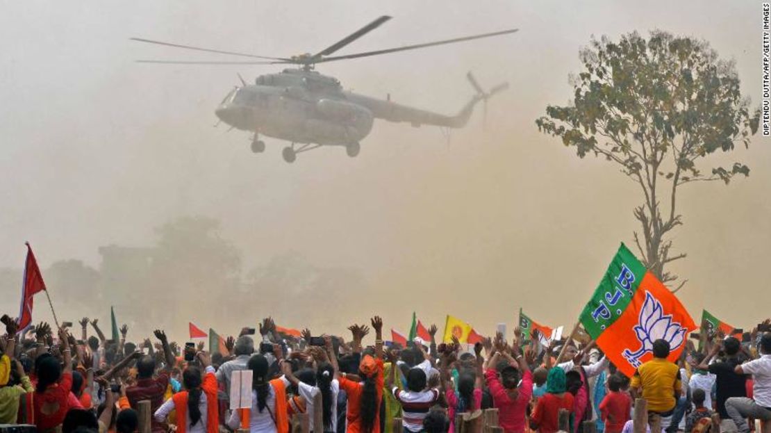 Partidarios del Partido Bharatiya Janata (BJP) saludan a un helicóptero que transporta al primer ministro de la India, Narendra Modi, a su llegada a una manifestación pública en Kawakhali, en las afueras de Siliguri, el 10 de abril de 2021.