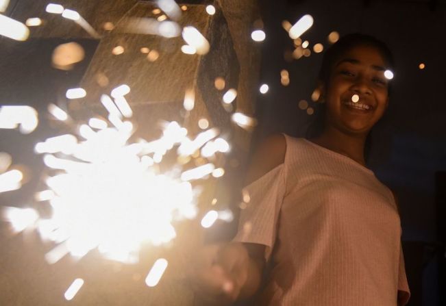 Una joven sostiene una luz de bengala durante las celebraciones del Año Nuevo en Colombo, Sri Lanka.