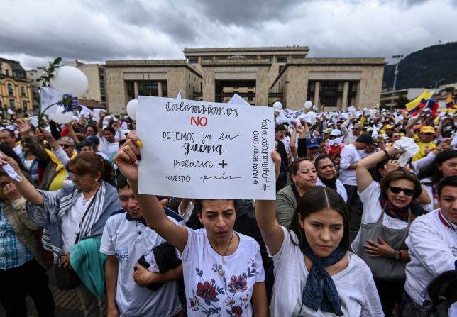 En Colombia, cientos de miles de personas salieron a las calles de las principales ciudades del país. En la foto: Los manifestantes sostienen un cartel que dice "Colombianos: No permitamos que la guerra polarice más a nuestro país" cuando se reúnen en la plaza de Bolívar en Bogotá.