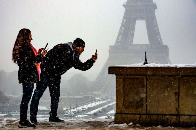 Turistas le toman fotos a una miniatura de la Torre Eiffel frente al monumento real.