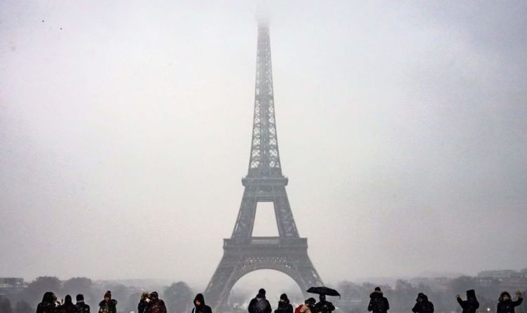 Turistas observan la Torre Eiffel mientras cae la nieve sobre París.