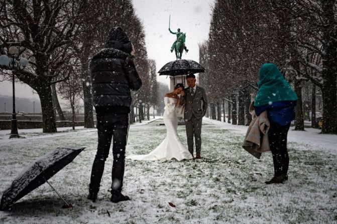 Una pareja de recién casados posa para las fotos de su boda bajo la nieve en París.