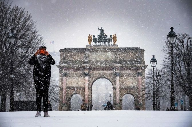 Un hombre toma fotos en el nevado Jardín de las Tullerías en París.