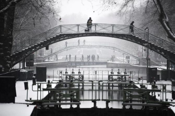 Personas usan un puente para cruzar el canal de Saint-Martin en una París invadida por la nieve.