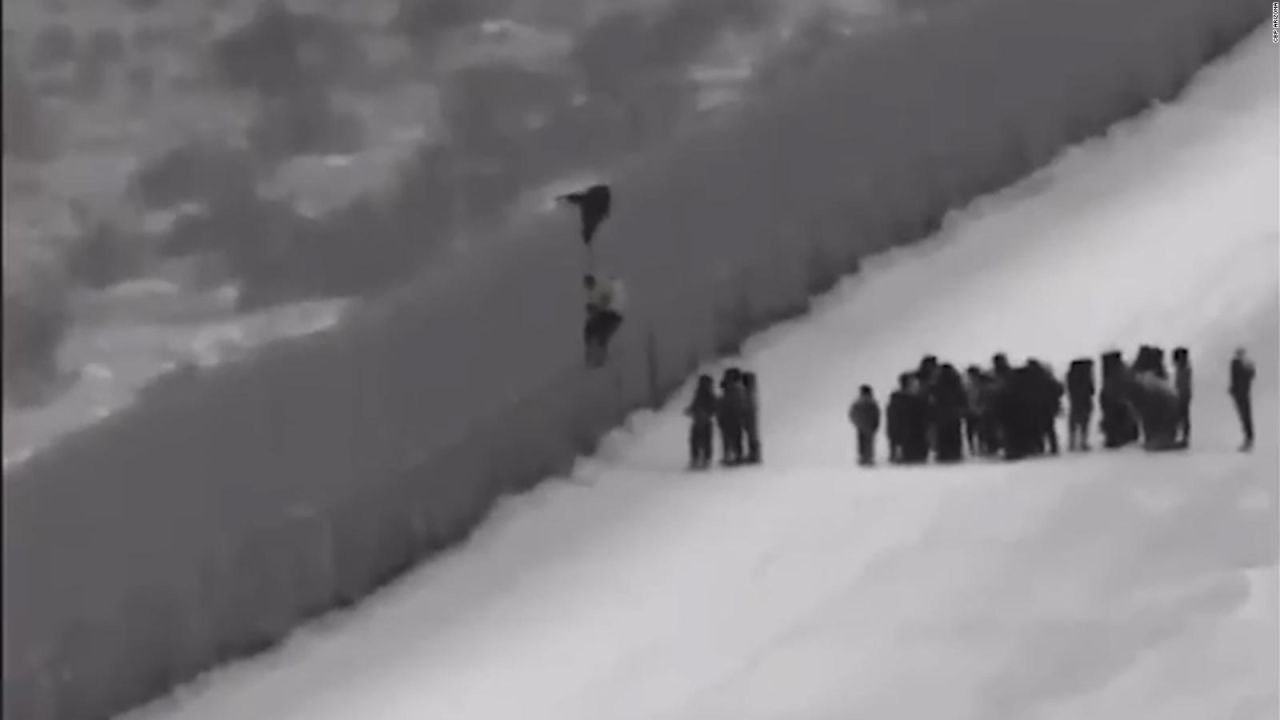 CNNE 608865 - migrantes cruzan el muro fronterizo usando una escalera