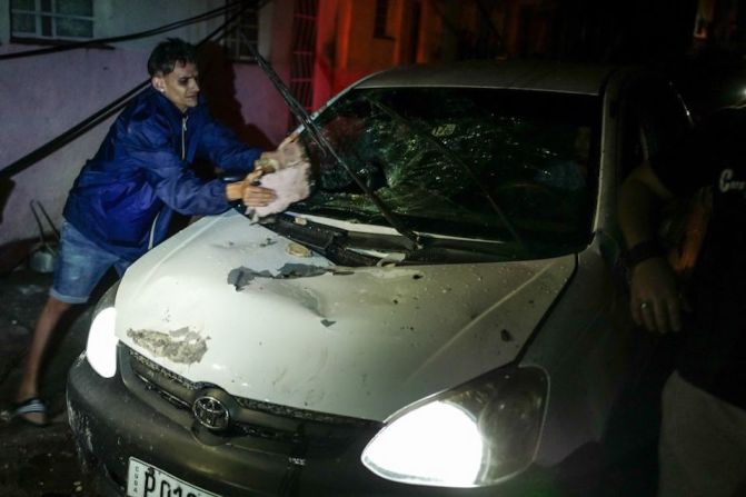 Un residente de Cuba remueve escombros que cayeron sobre su auto en el barrio de Luyano en La Habana.