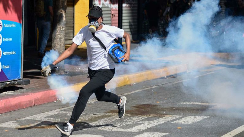 Un manifestante de la oposición corre con un bote de gas lacrimógeno el 23 de enero de 2019. (Federico Parra / AFP / Getty Images).