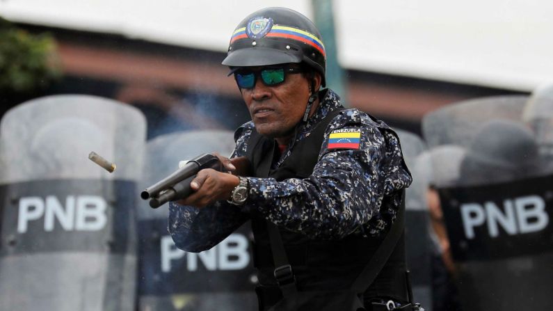 Un agente de la Policía Nacional Bolivariana dispara balas de goma en Caracas.