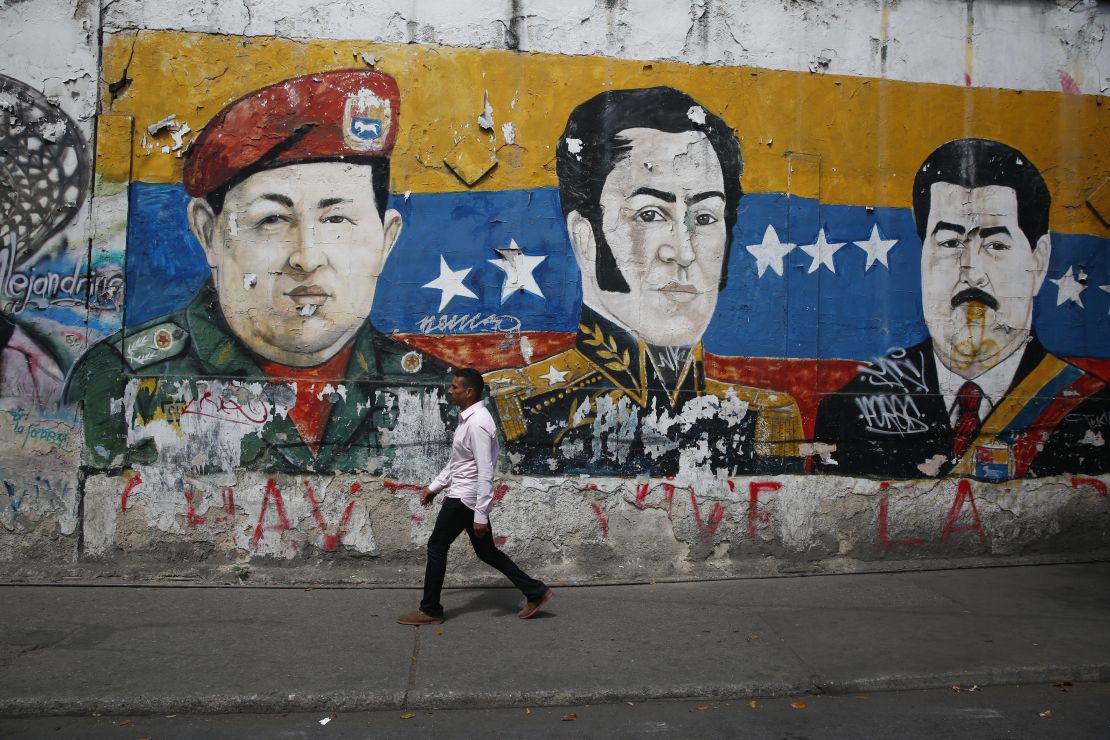 En Caracas, un hombre pasa junto a un mural que representa al fallecido presidente de Venezuela Hugo Chávez, al héroe de la independencia latinoamericana Simón Bolívar y al presidente de Venezuela Nicolás Maduro.