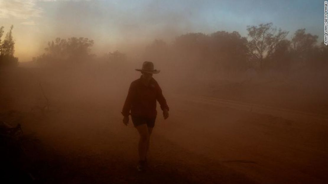 Un granjero australiano camina en medio de una nube de polvo en sus tierras.