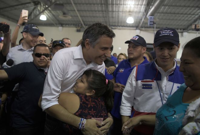 El candidato presidencial salvadoreño Carlos Calleja, de la Alianza Republicana Nacional (ARENA), es recibido por una niña en un colegio electoral durante las elecciones presidenciales salvadoreñas, en San Salvador, el 3 de febrero de 2019.