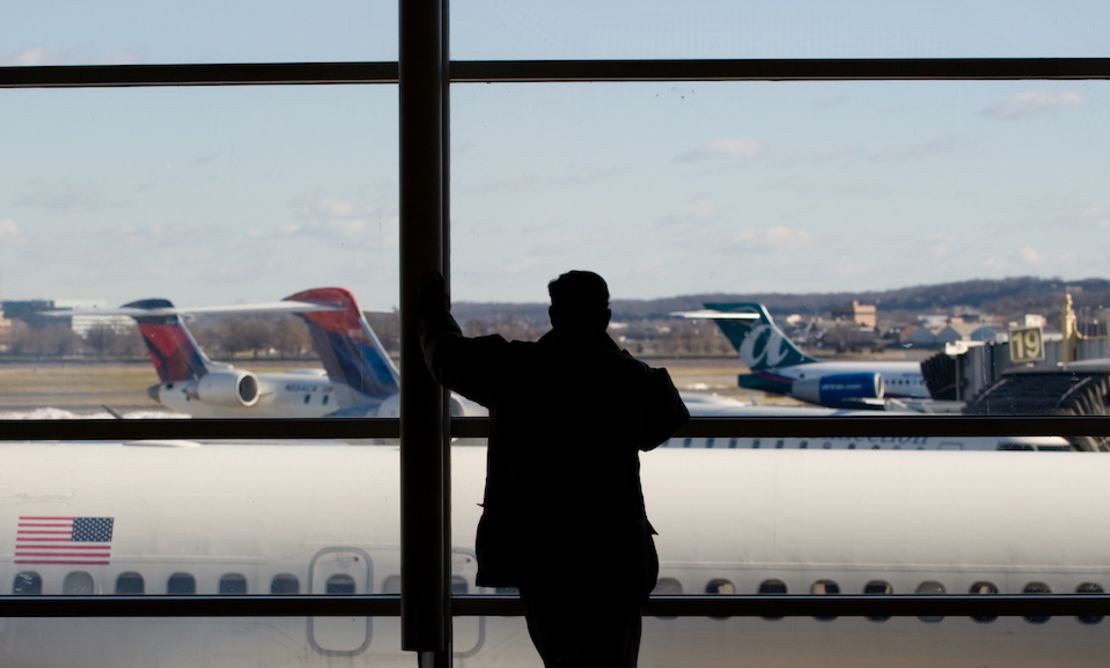 CNNE 615860 - a man looks out the window at airplanes