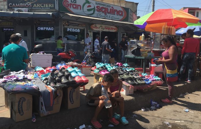 Dos niños sentados frente a un puesto callejero de venta de zapatos en Villa del Rosario, Norte de Santander.