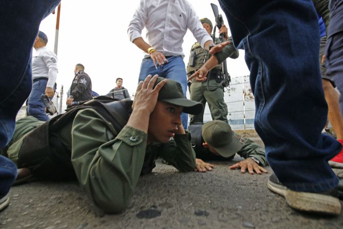 Dos soldados venezolanos yacen en el suelo mientras son detenidos por la policía colombiana después de conducir a Colombia en un vehículo blindado desde el lado venezolano del puente internacional Simón Bolívar en Cúcuta.