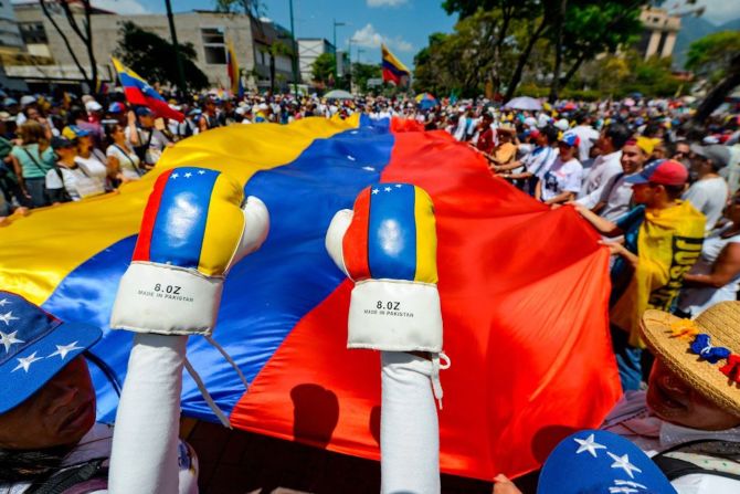 Una gran bandera de Venezuela se despliega en las calles de Caracas mientras manifestantes esperan al líder opositor Juan Guaidó.