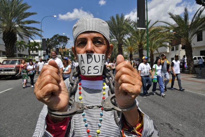 Este manifestante tiene sus muñecas atadas con esposas y la boca tapada con una frase que dice "Maduro asesino", criticando al presidente de Venezuela contra quien miles de manifestantes marchan el 4 de marzo.