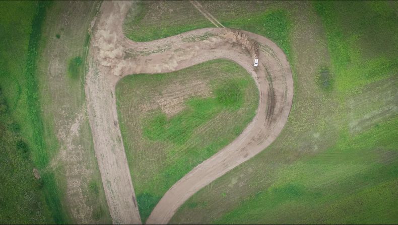 Vista aérea de Fernando Scarlatta, piloto de rally, tomando una curva en un camino de tierra.