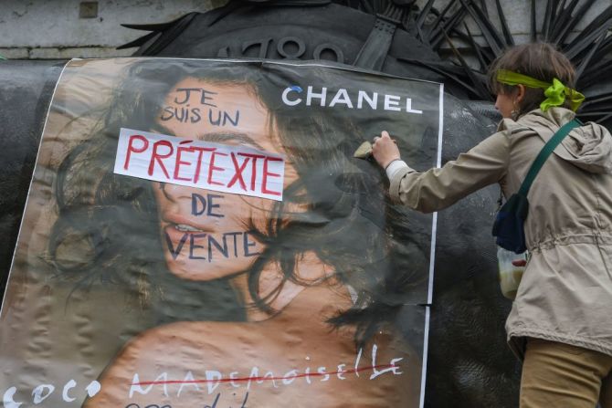 Una mujer pega un aviso publicitario personalizado que dice "Soy una excusa para vender", durante una manifestación en la Place de la République, en París, Francia, el 8 de marzo de 2018.